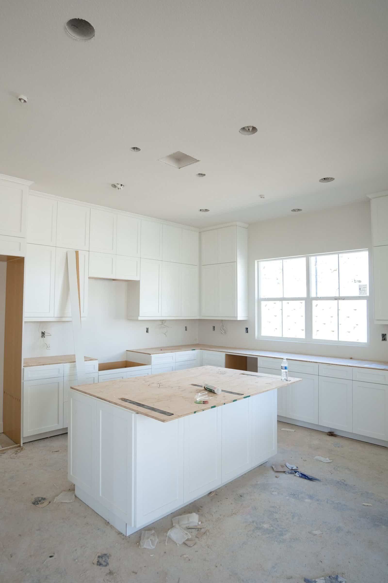 Bright white kitchen cabinets under construction in a new home renovation project, showcasing professional interior painting and cabinetry services by Central Coast Painter Corp.